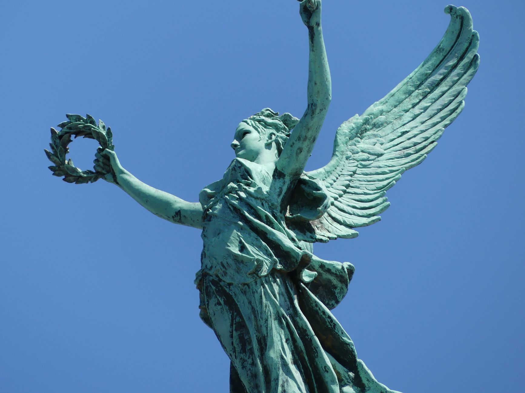 Sculpture of Winged Victory with laurel wreath against a clear blue sky in Brussels
