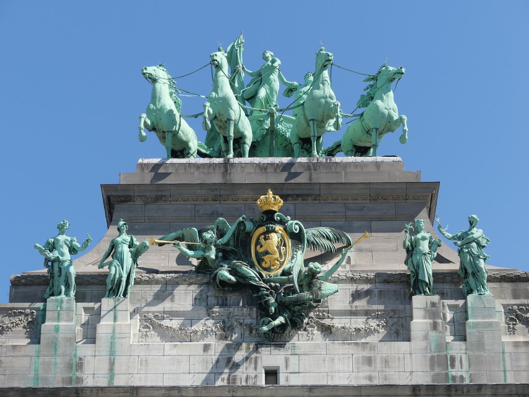 Statues atop the Cinquantenaire Arch in Brussels under a clear blue sky